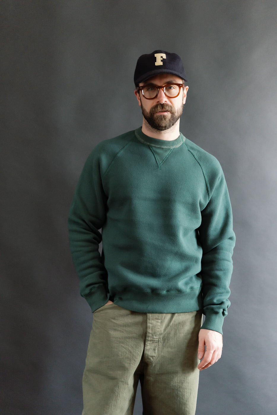 Male model 5'9 165lbs athletic build wearing vintage forest green crewneck sweatshirt, front view, showing full body fit and raglan sleeves for Dant contemporary casual apparel
