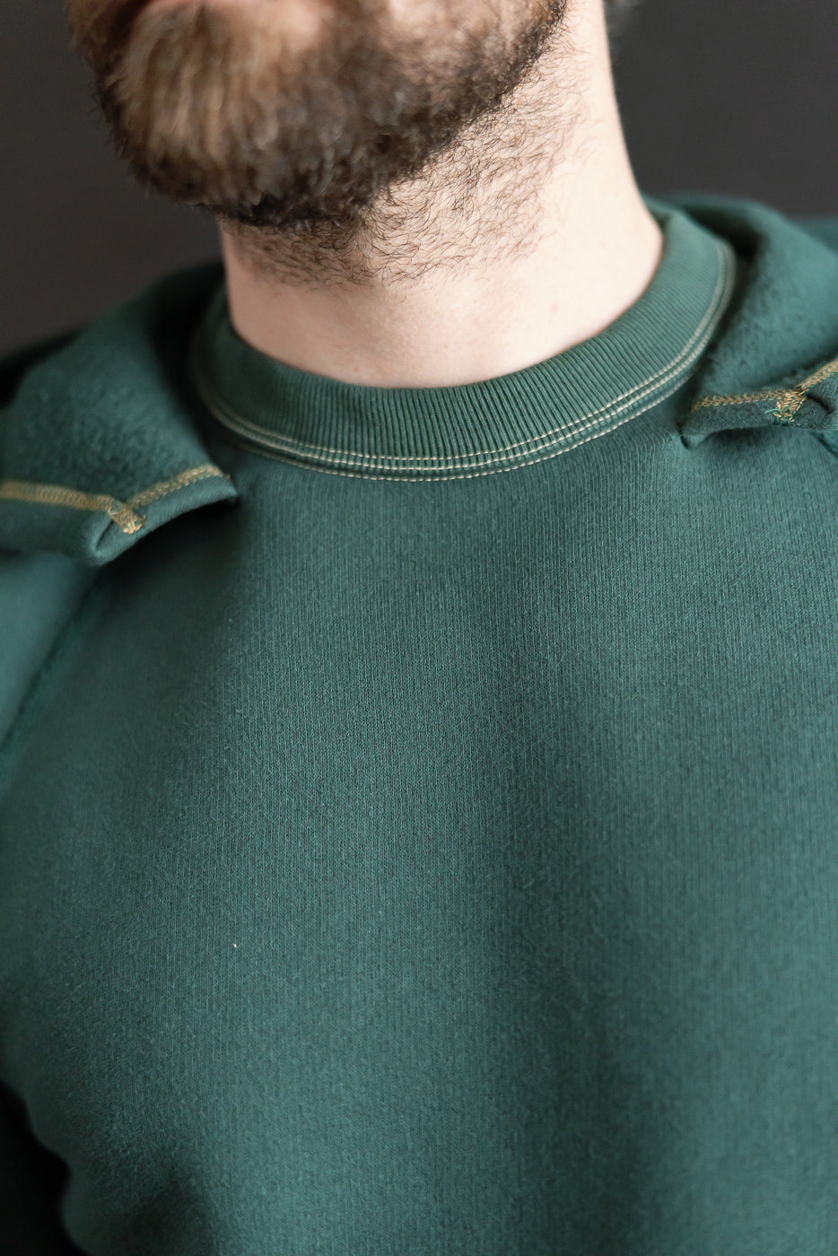 Close-up of front collar on super fluffy knit raglan hoodie, vintage forest green, worn by male model 5'9