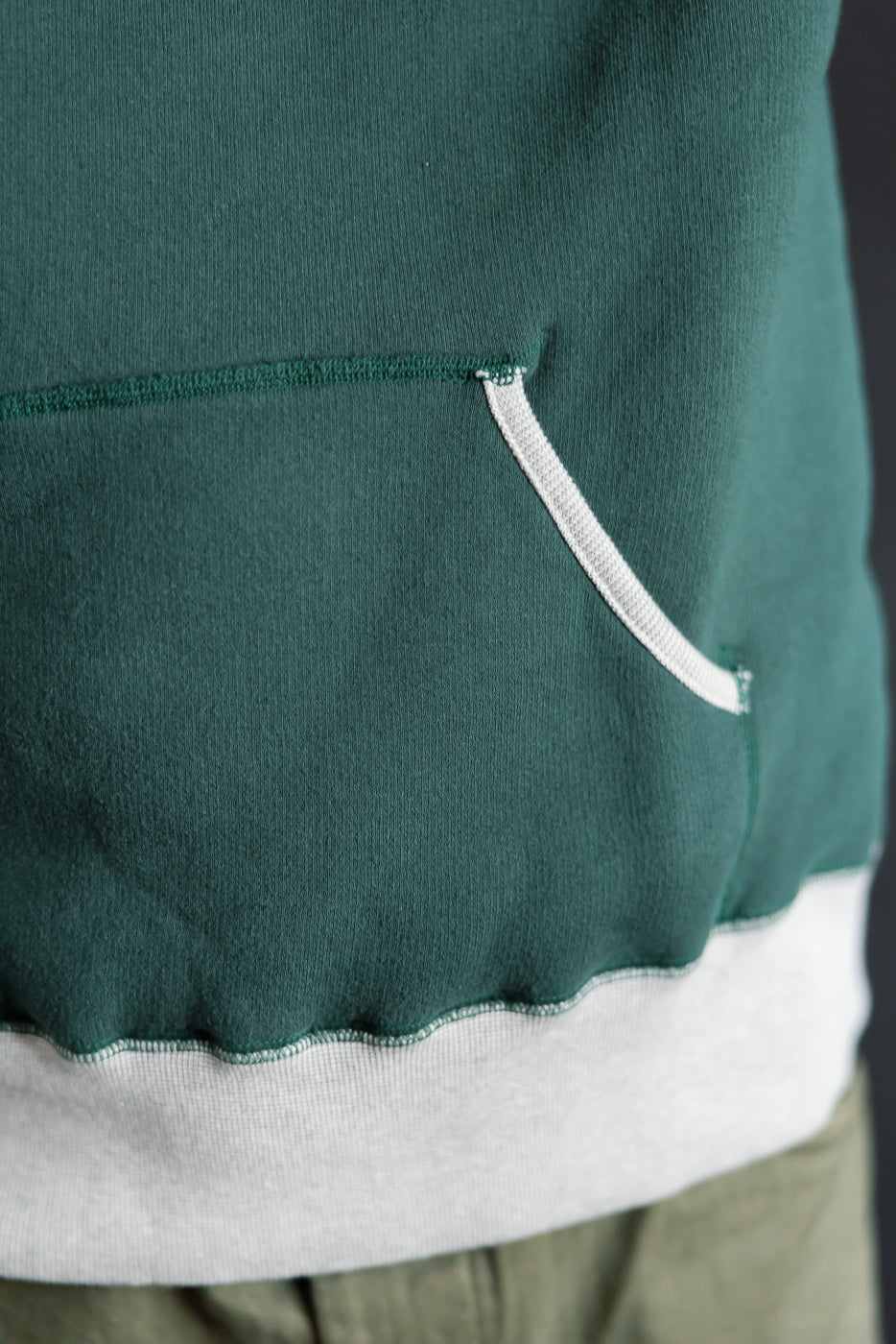 Close-up of front pocket and hem on Loop & Weft 2-tone forest green hoodie, showing fabric texture