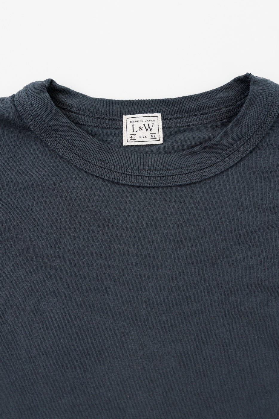 Close-up front view of dark gray crew neck tee, showing L&W tag, ribbed collar, and fabric texture
