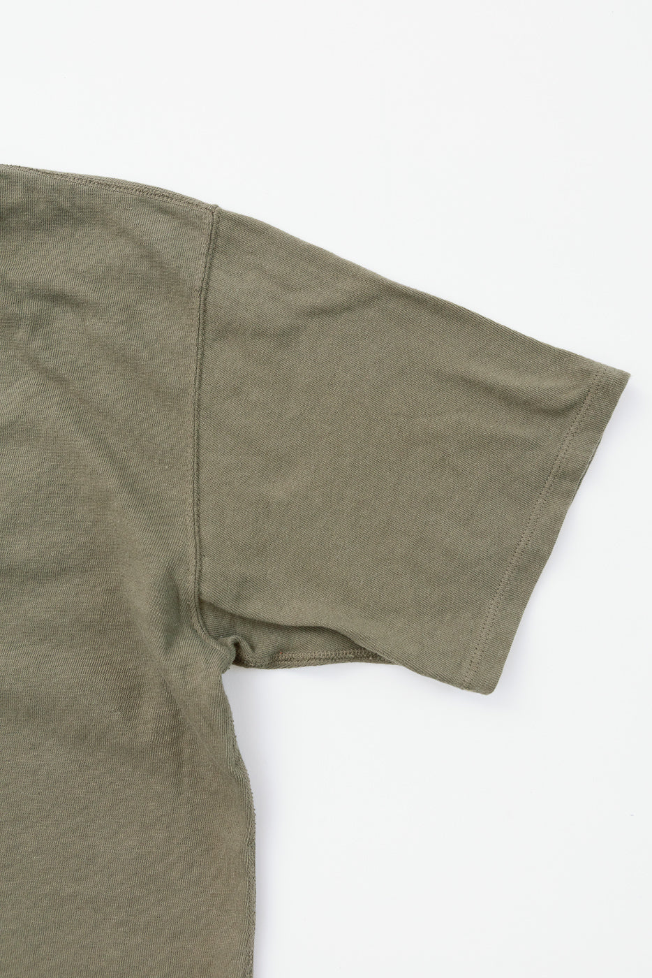 Close-up of olive green t-shirt sleeve, showcasing ribbed texture and hem detail