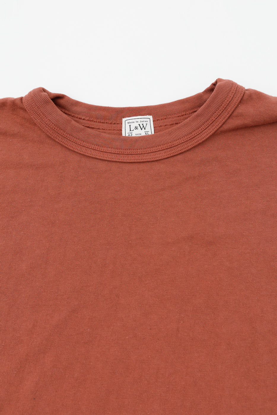 Close-up of rust-colored tee's collar, showing L&W tag, size XL, made in Japan