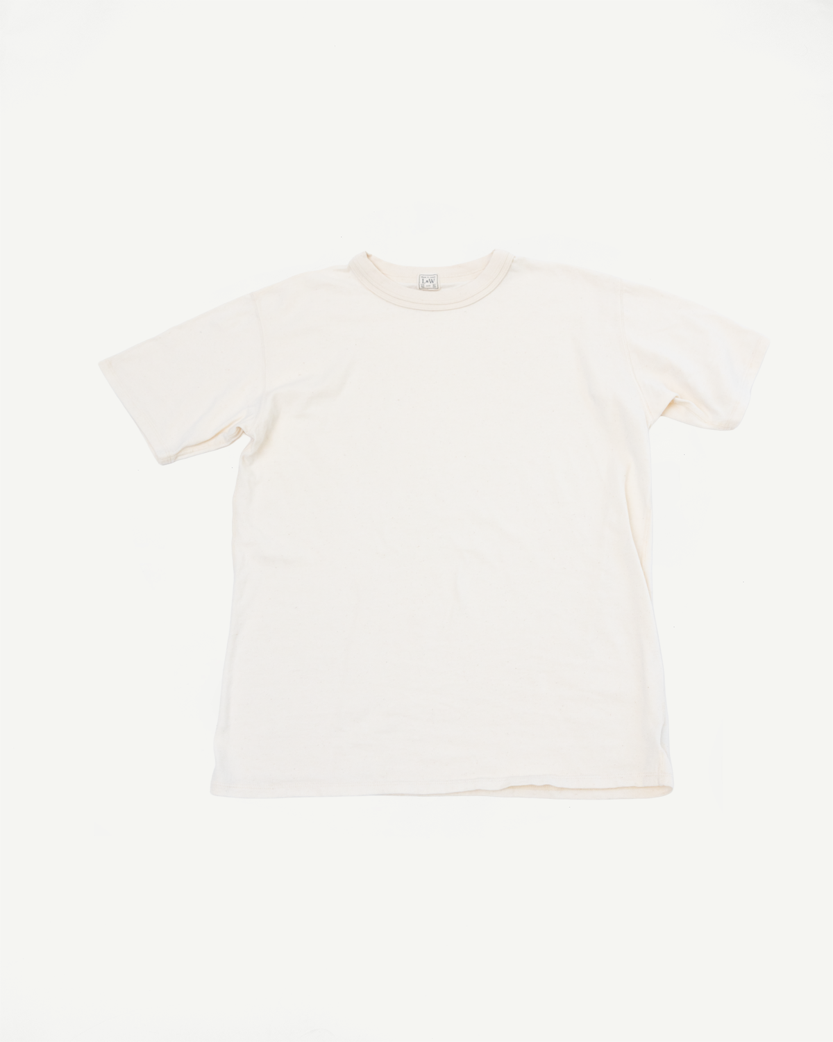 Cream cotton t-shirt flat lay, front view, showing crew neck and tag detail