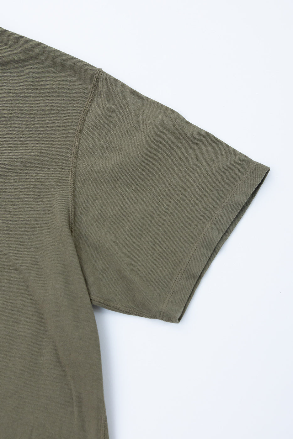 Olive green tee close-up showing sleeve hem and shoulder seam detail, front view
