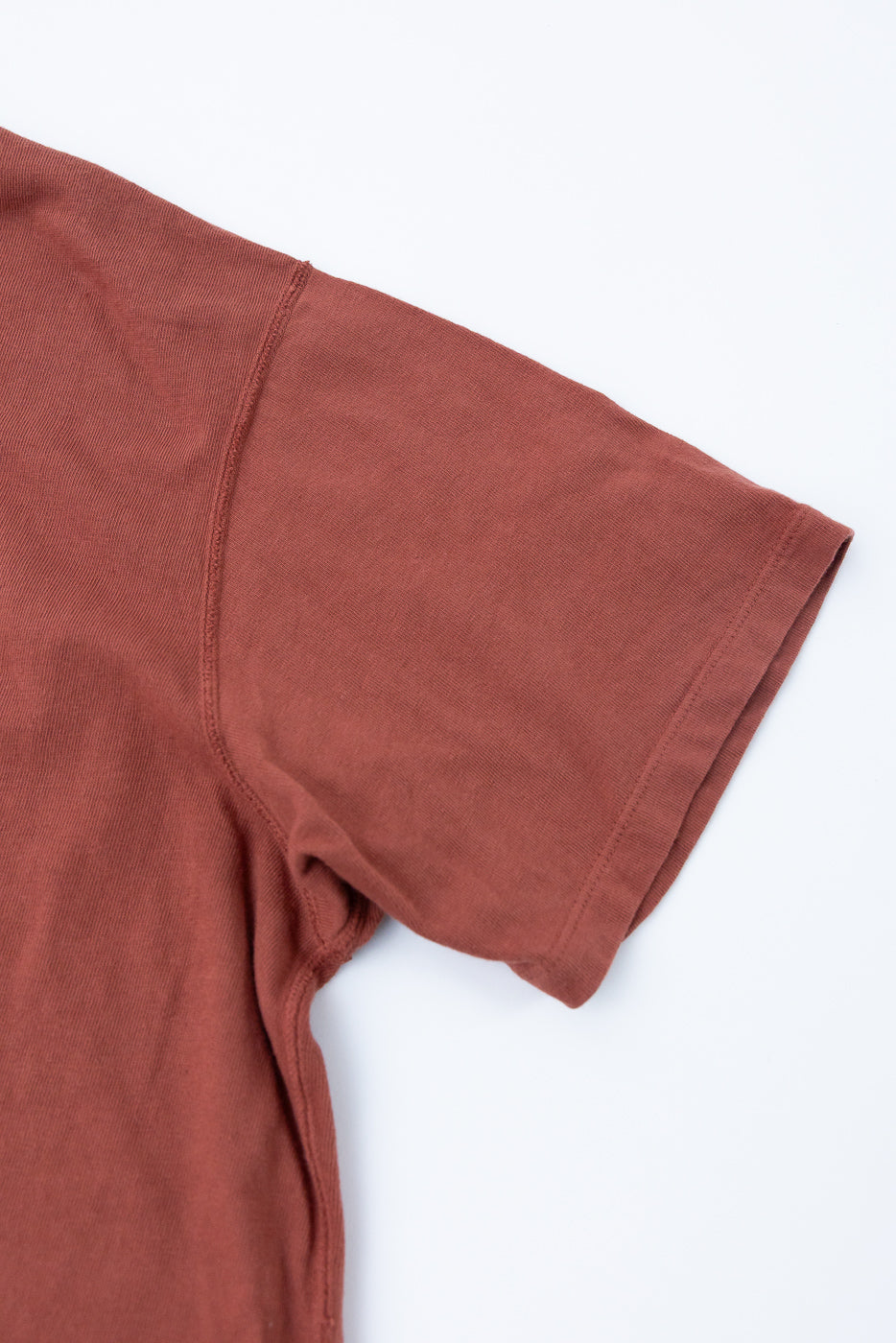 Close-up front view of rust-colored tee, showing short sleeve hem and shoulder seam detail