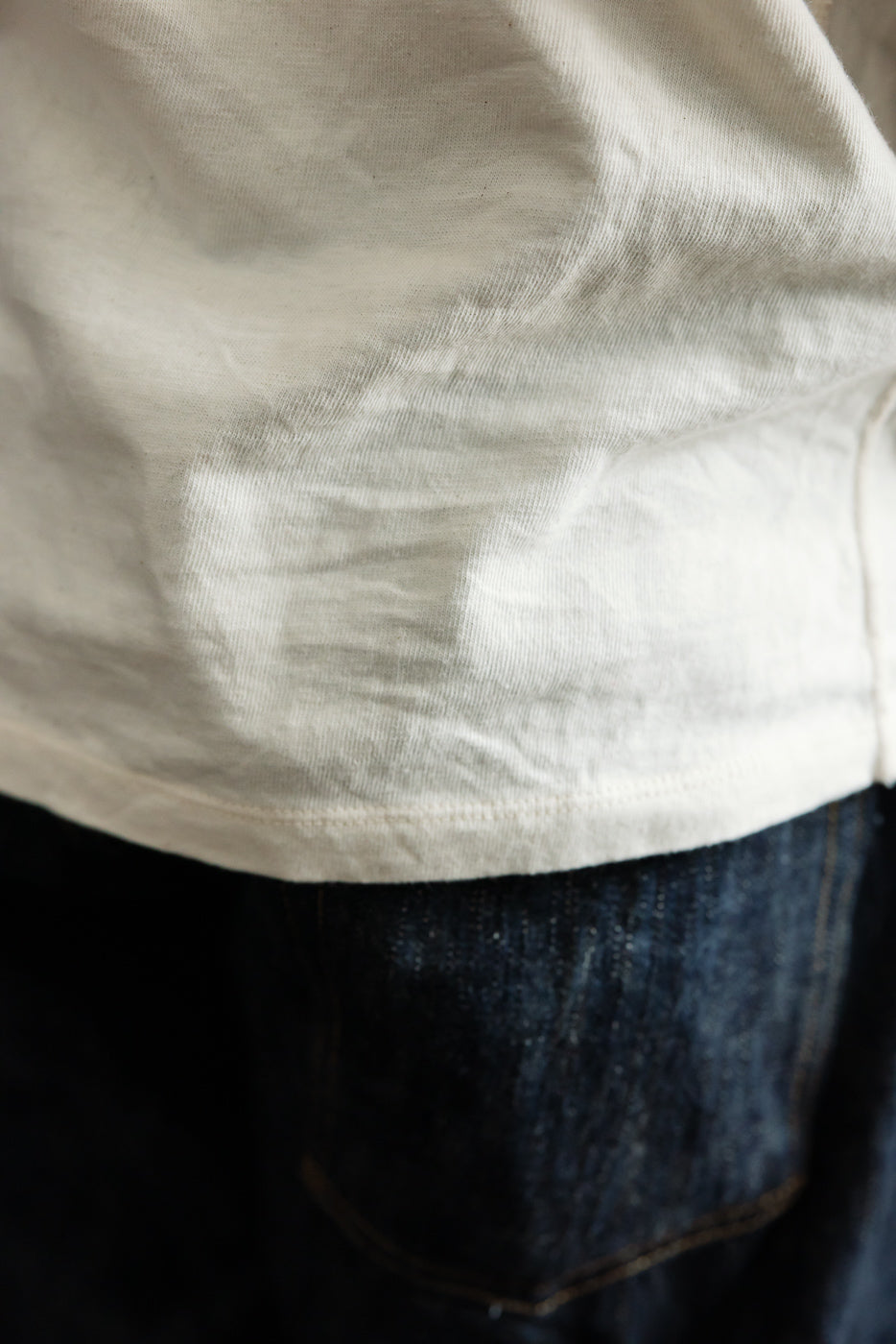 Close-up front hem of off-white tee on male model, 5'9