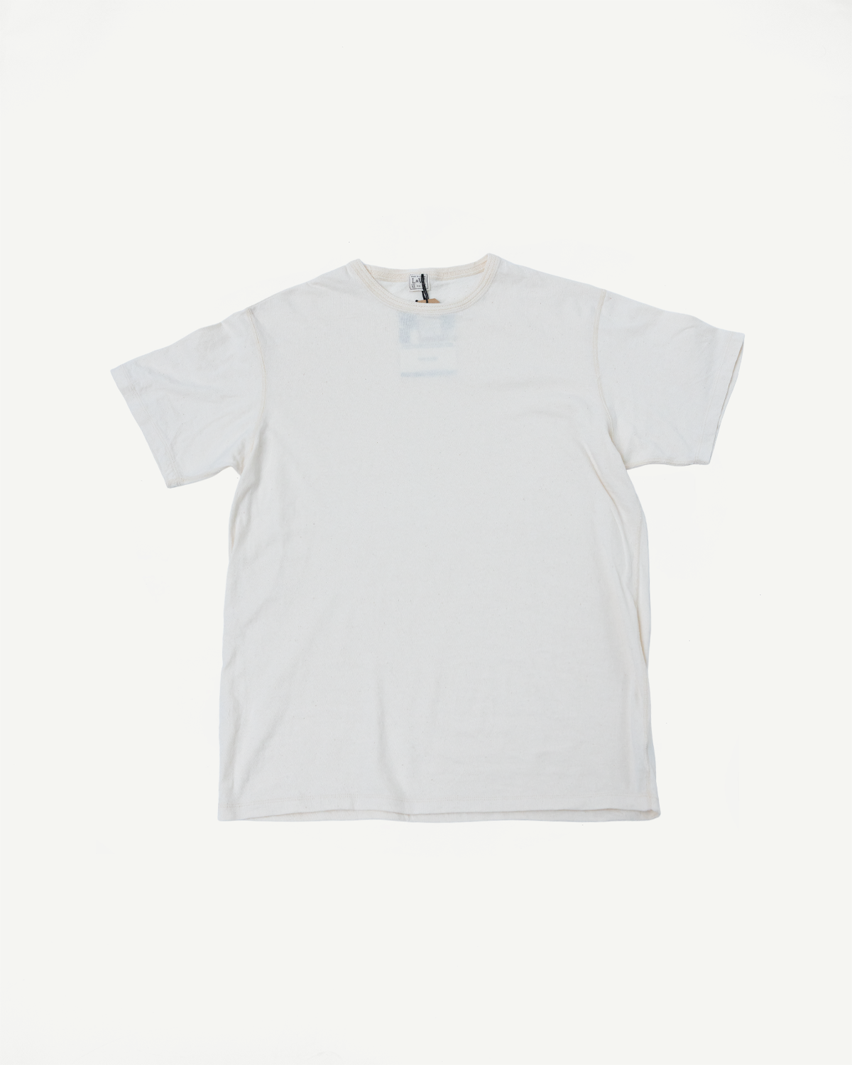 Front view of off-white crew neck t-shirt, flat lay, showing tag detail and relaxed fit