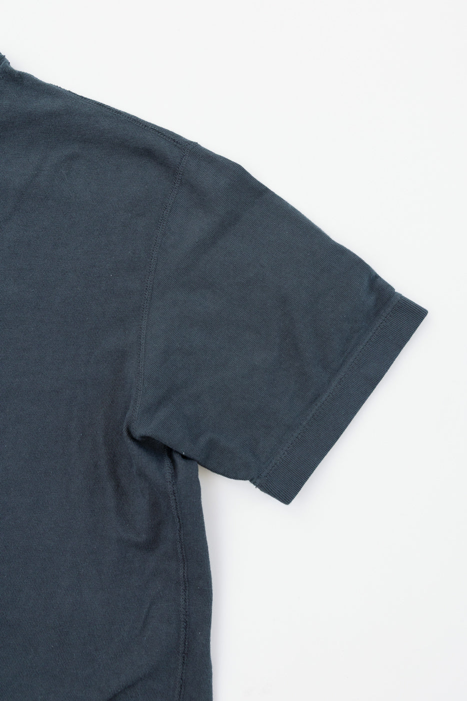 Close-up of dark gray t-shirt sleeve, showcasing ribbed hem and fabric texture, front view