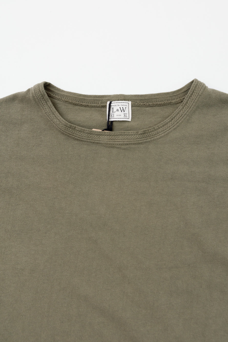 Close-up front view of olive green crew neck tee, showing L&W tag, ribbed collar, and fabric texture.