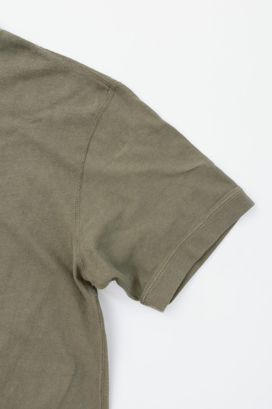 Close-up of olive green t-shirt sleeve, showcasing ribbed hem and fabric texture, front view