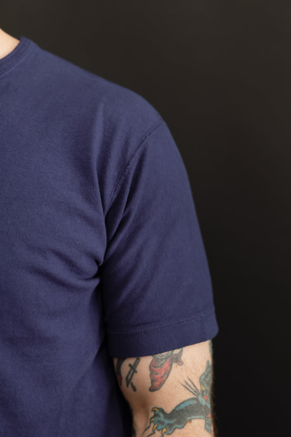Close-up side view of navy blue short-sleeve tee on male model, 5'9