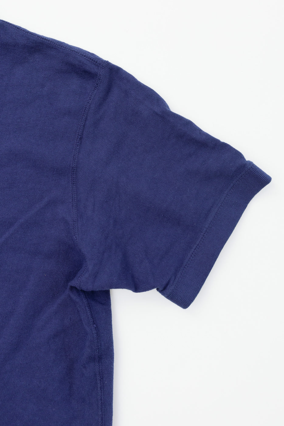 Navy blue t-shirt close-up showing left sleeve hem and ribbed cuff detail, front view