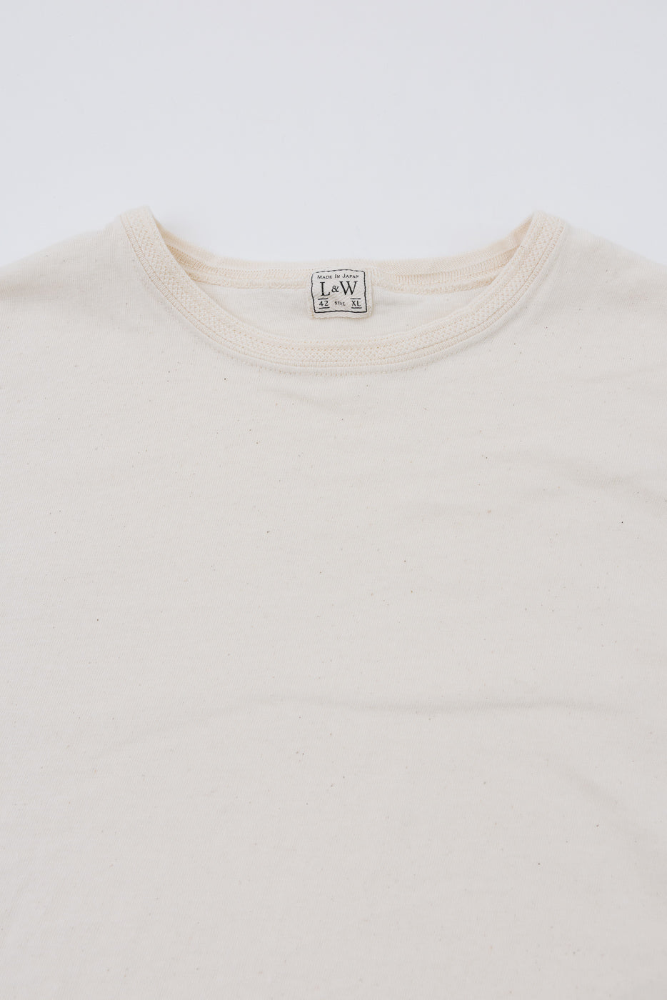 Close-up front view of cream crew neck tee, showing L&W tag, Made in Japan, size XL, soft cotton texture