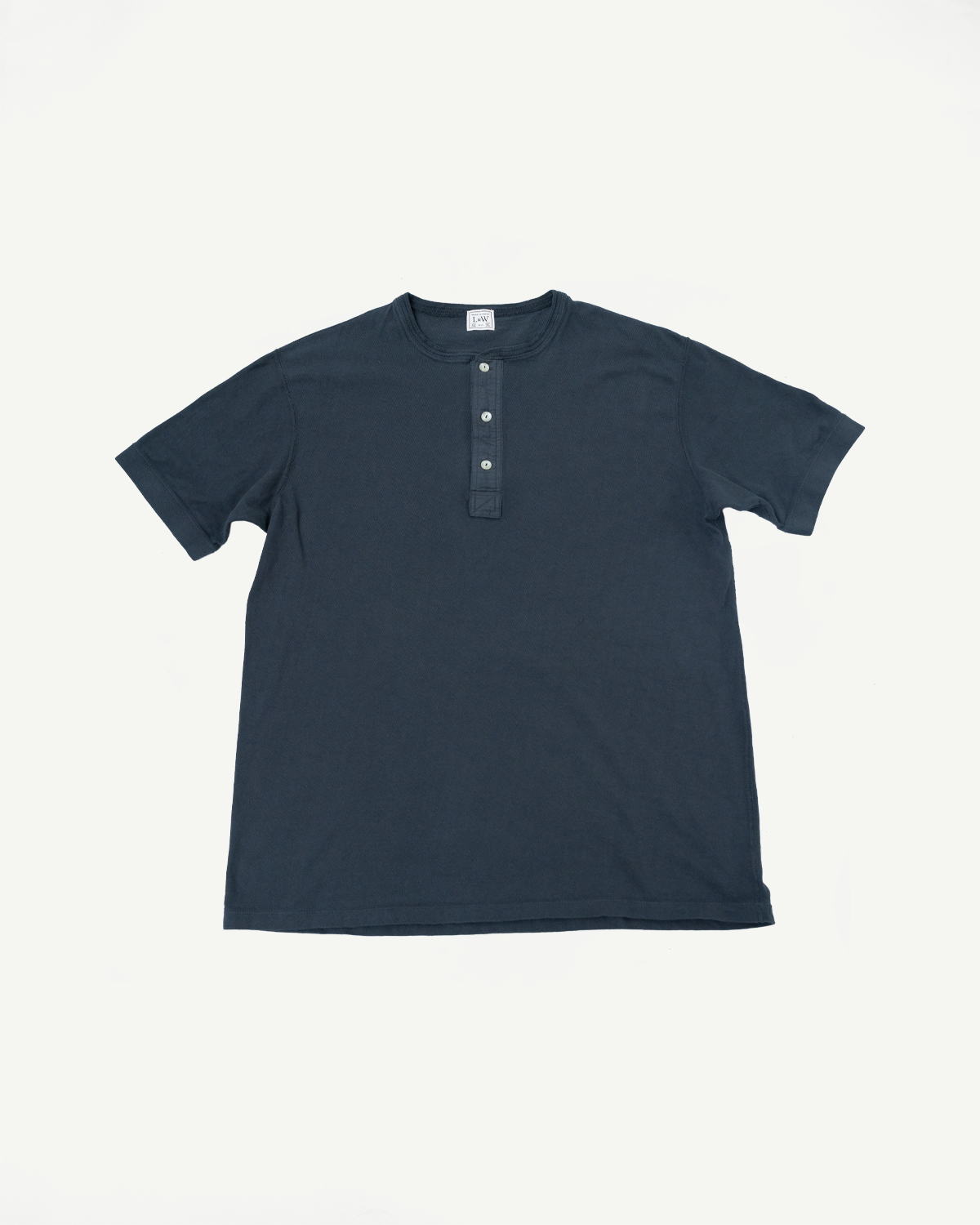Navy blue short-sleeve henley shirt, front view flat lay, ribbed texture, 3-button placket, crew neck, tag visible