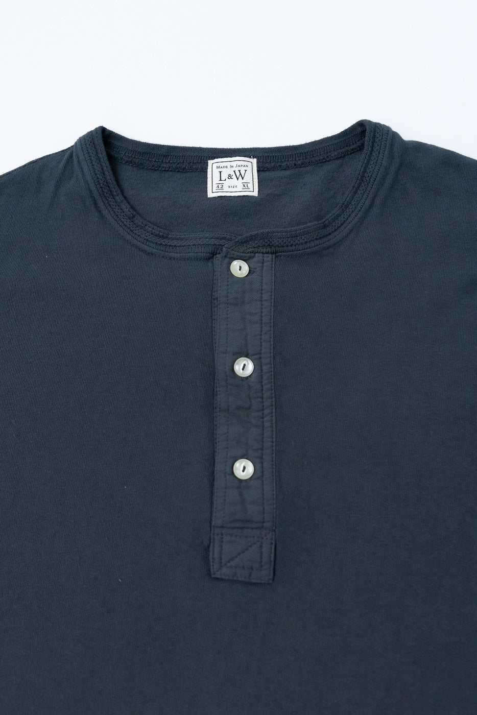 Close-up front of dark henley shirt showing buttons, collar, and L&W tag, made in Japan