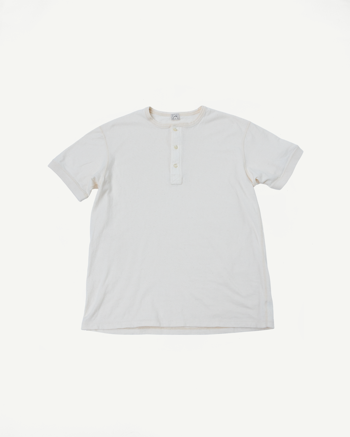 Flat lay front view of off-white short sleeve henley tee, showing ribbed collar, placket buttons, and tag detail.