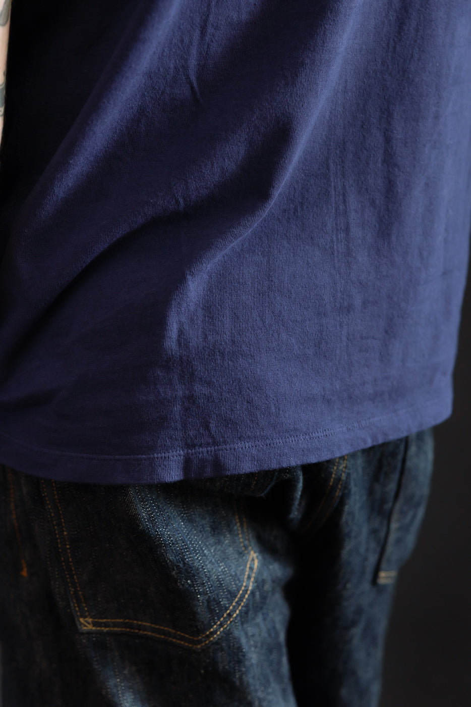 Close-up of navy t-shirt hem and selvedge denim pocket, male model, athletic build