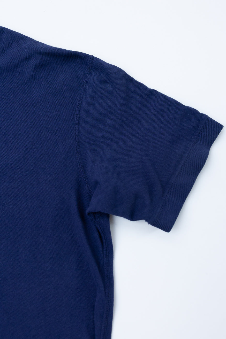 Navy blue t-shirt close-up, front shoulder and sleeve seam detail, ribbed cuff, soft cotton texture