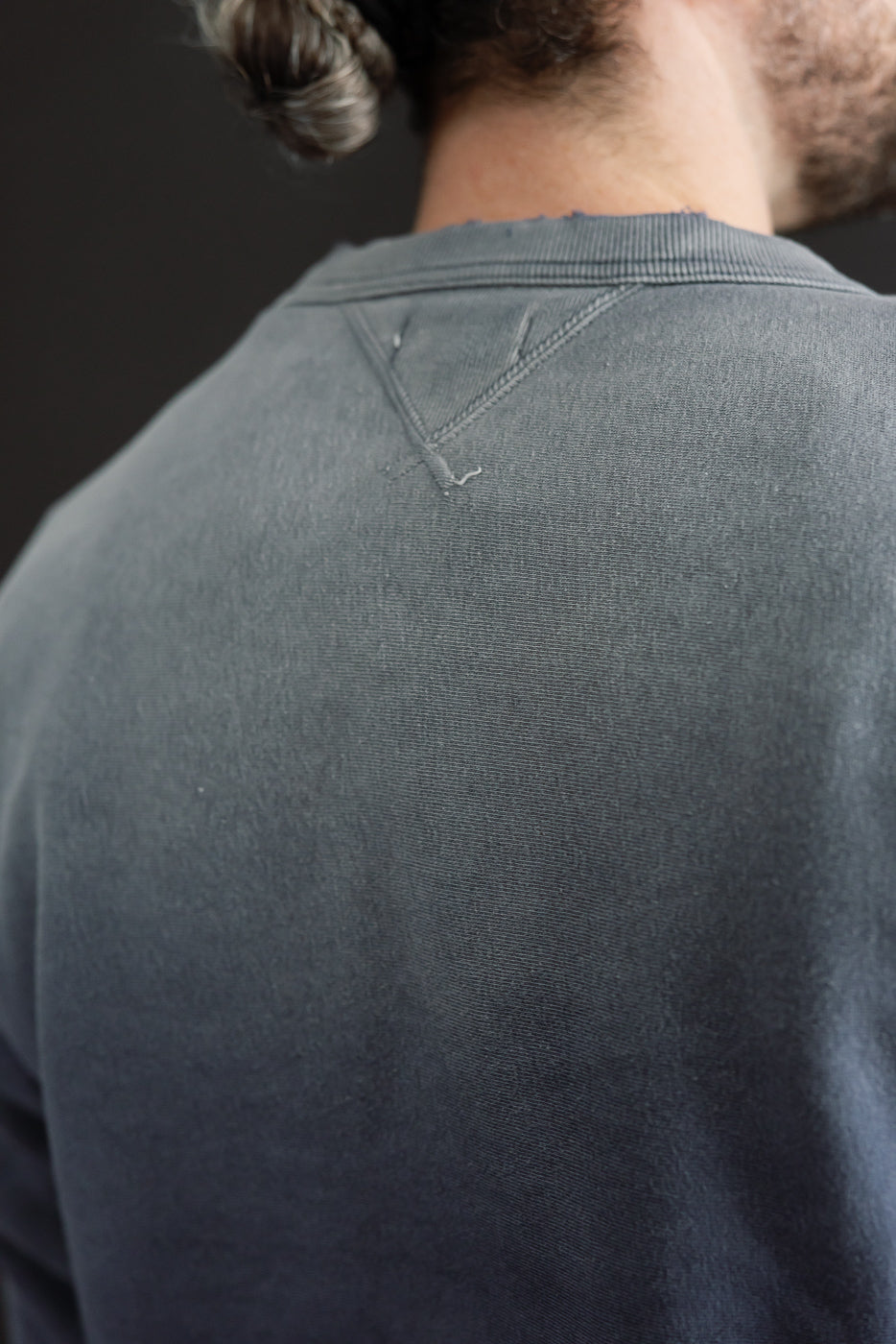 Close-up back view of a grey sweatshirt showing the neckline and fabric texture.