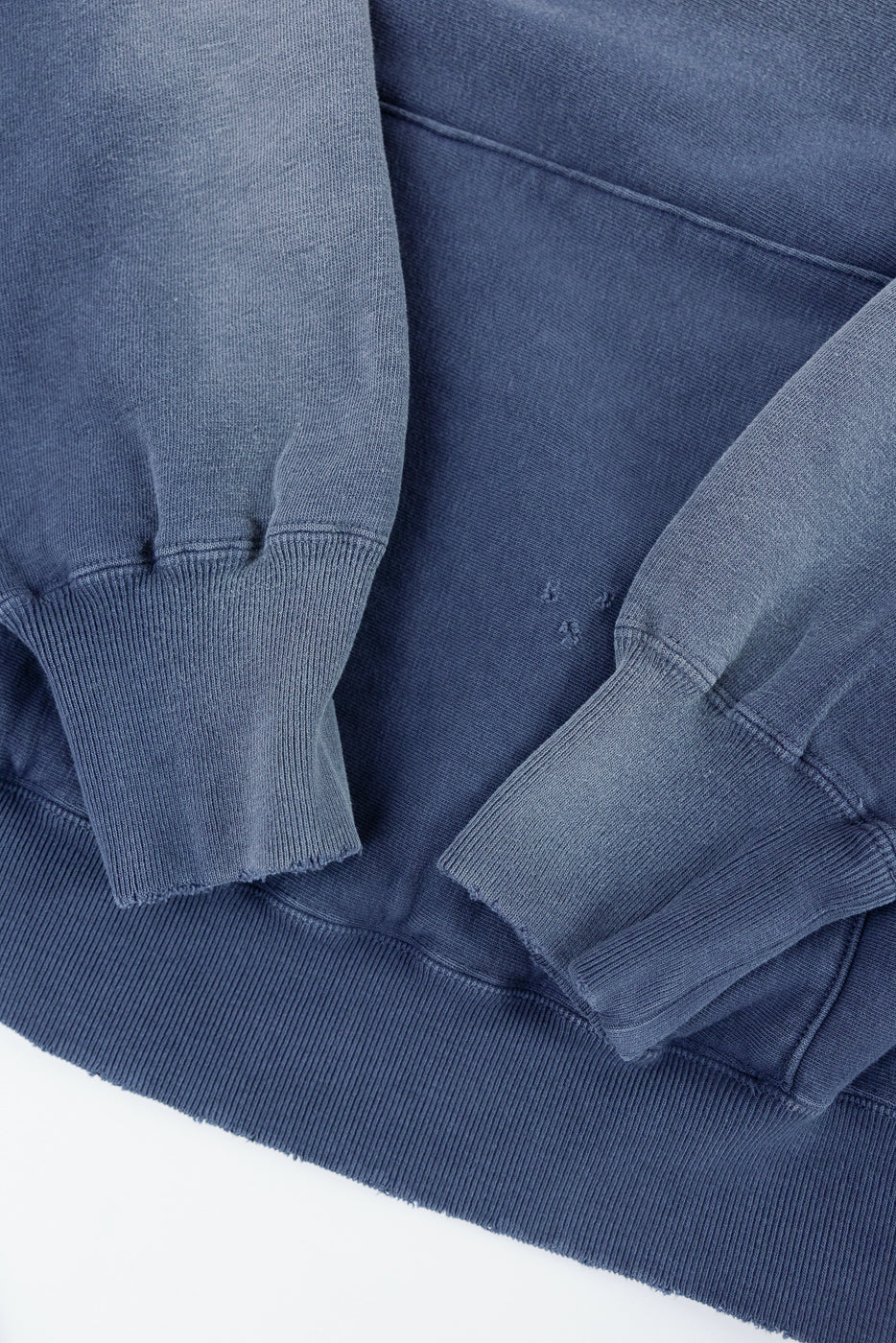 Close-up front view of a blue sweatshirt showing ribbed cuffs and hem texture.