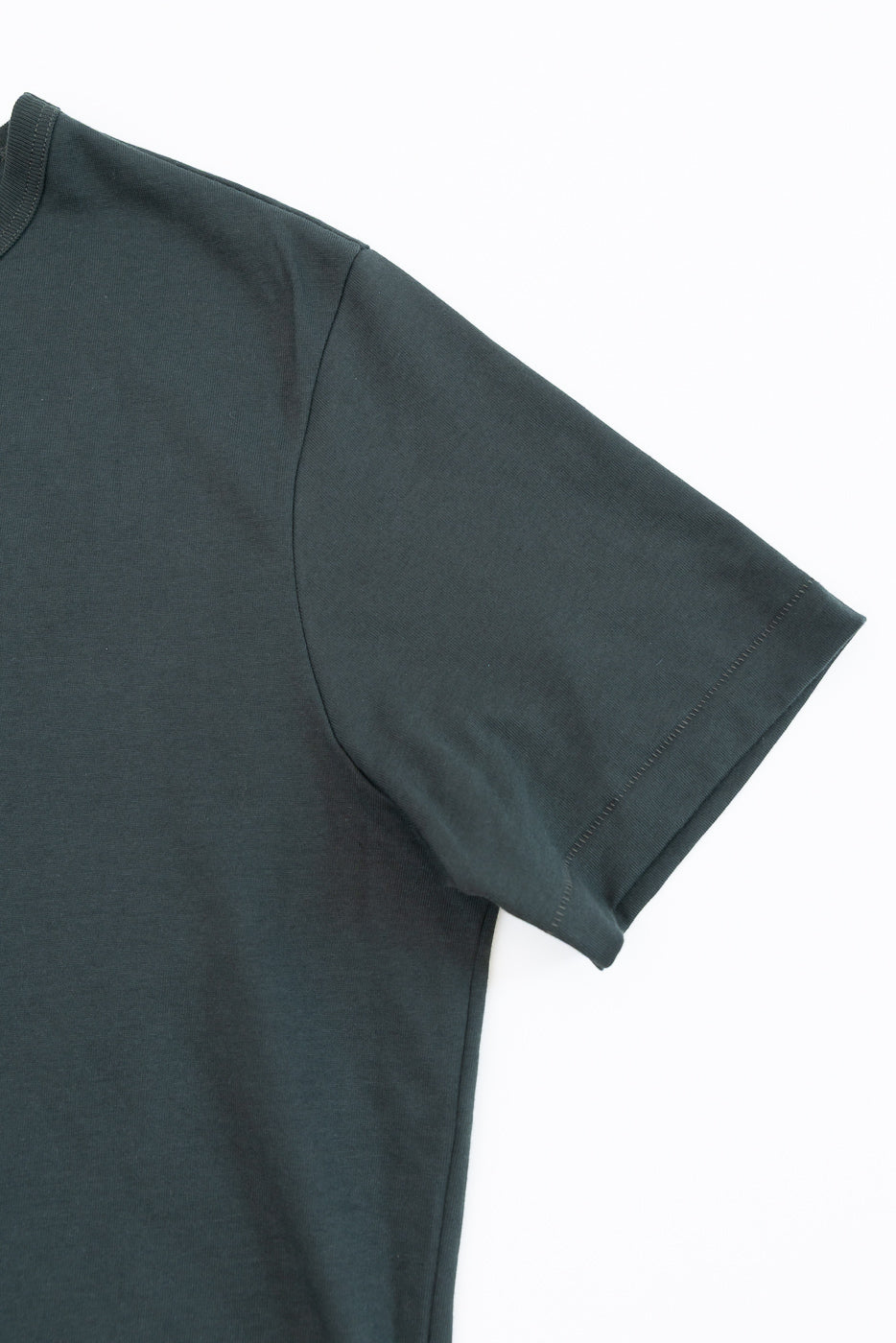Close-up of the front right sleeve and shoulder of a dark green t-shirt.