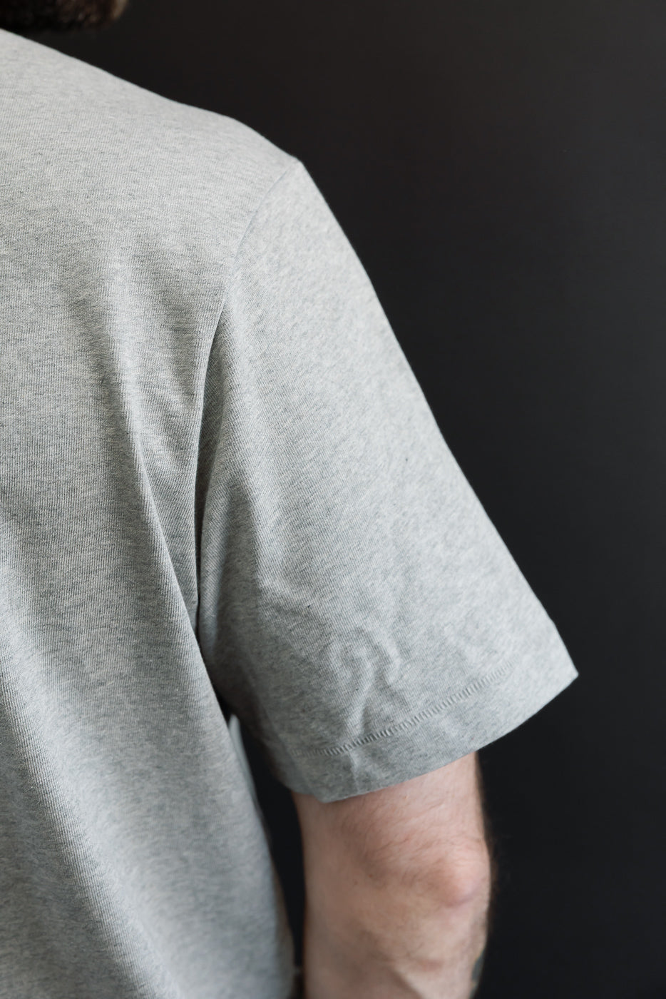 Close-up of the side sleeve and fabric texture of a grey t-shirt on a male model, 5'9