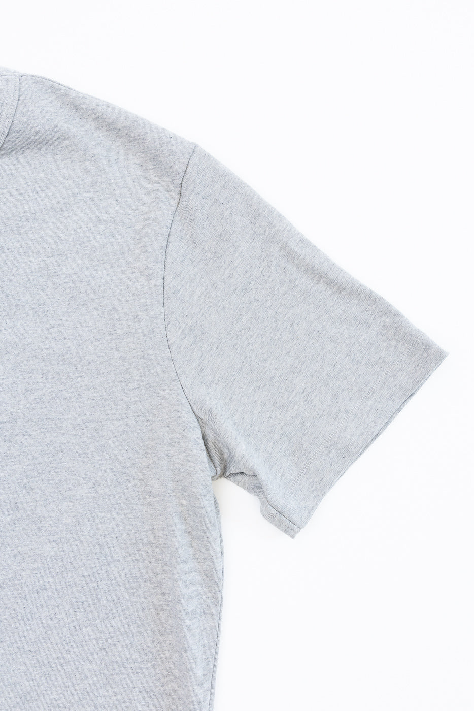 Close-up of the right sleeve and shoulder seam of a grey heathered cotton t-shirt.