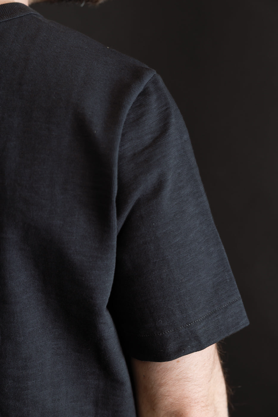 Close-up of charcoal heavy T-shirt on male model, right back shoulder and sleeve detail