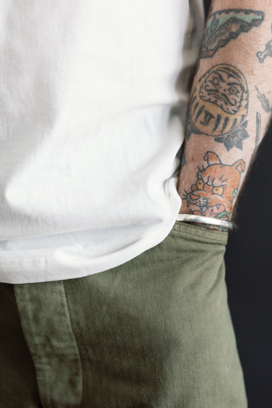 Close-up side view of Merz b. Schwanen white loopwheeled T-shirt hem and olive pants on a male model, 5'9
