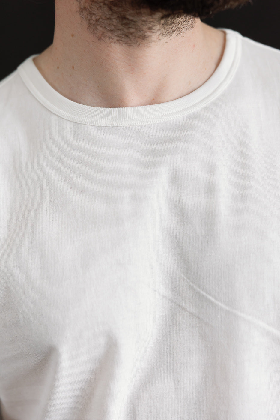 Close-up of front chest and collar on Merz b. Schwanen white loopwheeled T-shirt, male model, classic fit, athletic build