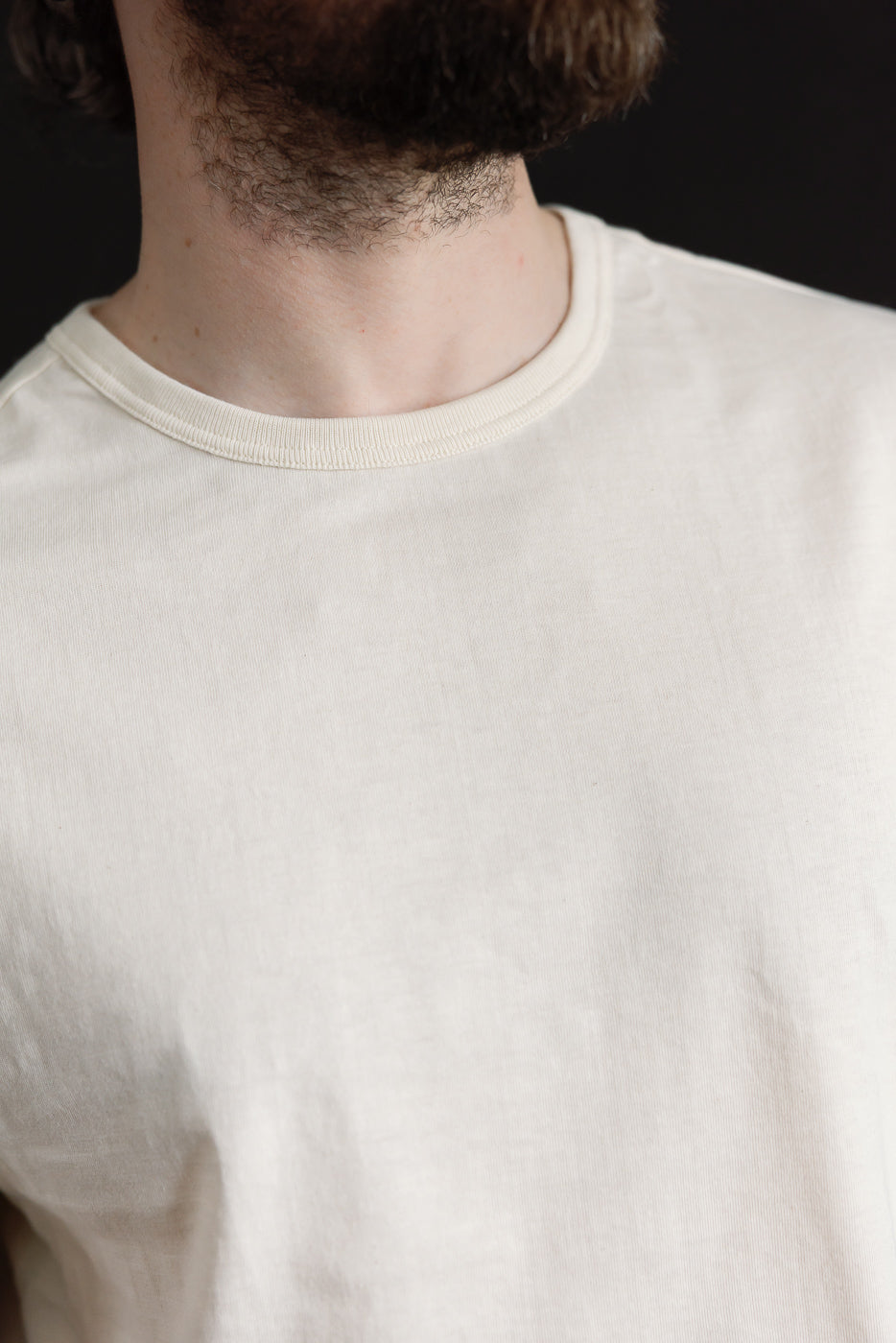 Close-up front of Merz b. Schwanen 1950s loopwheeled T-shirt in nature color, classic ribbed crew neck on male model, 5'9