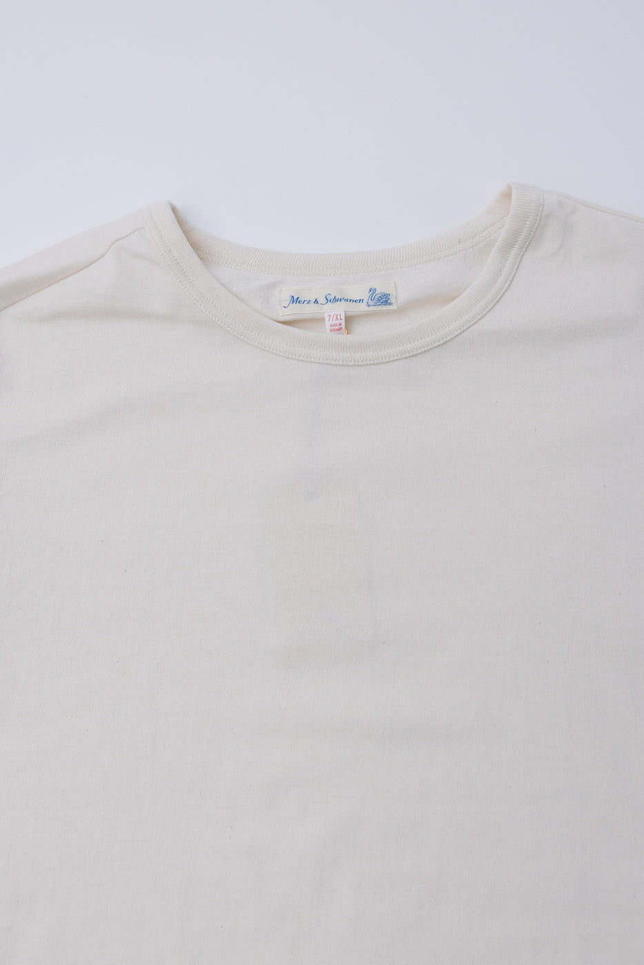 Close-up front view of Merz B. Schwanen 1950s loopwheeled T-shirt collar, fabric texture, and neck tag in natural color at Dant.