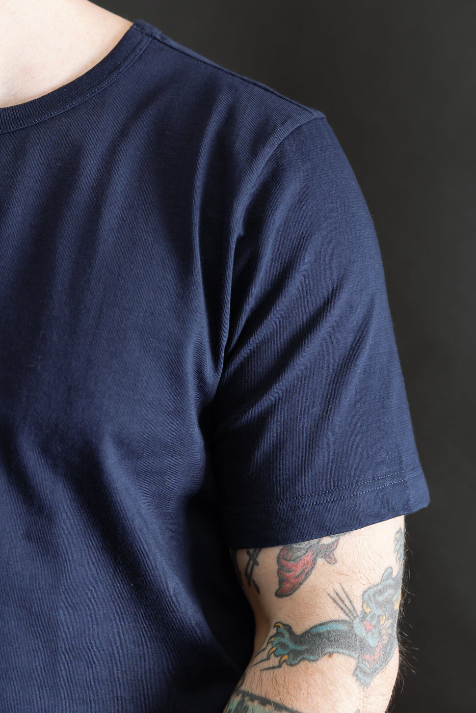 Close-up of front upper right side of navy blue loopwheeled T-shirt on male model, 5'9