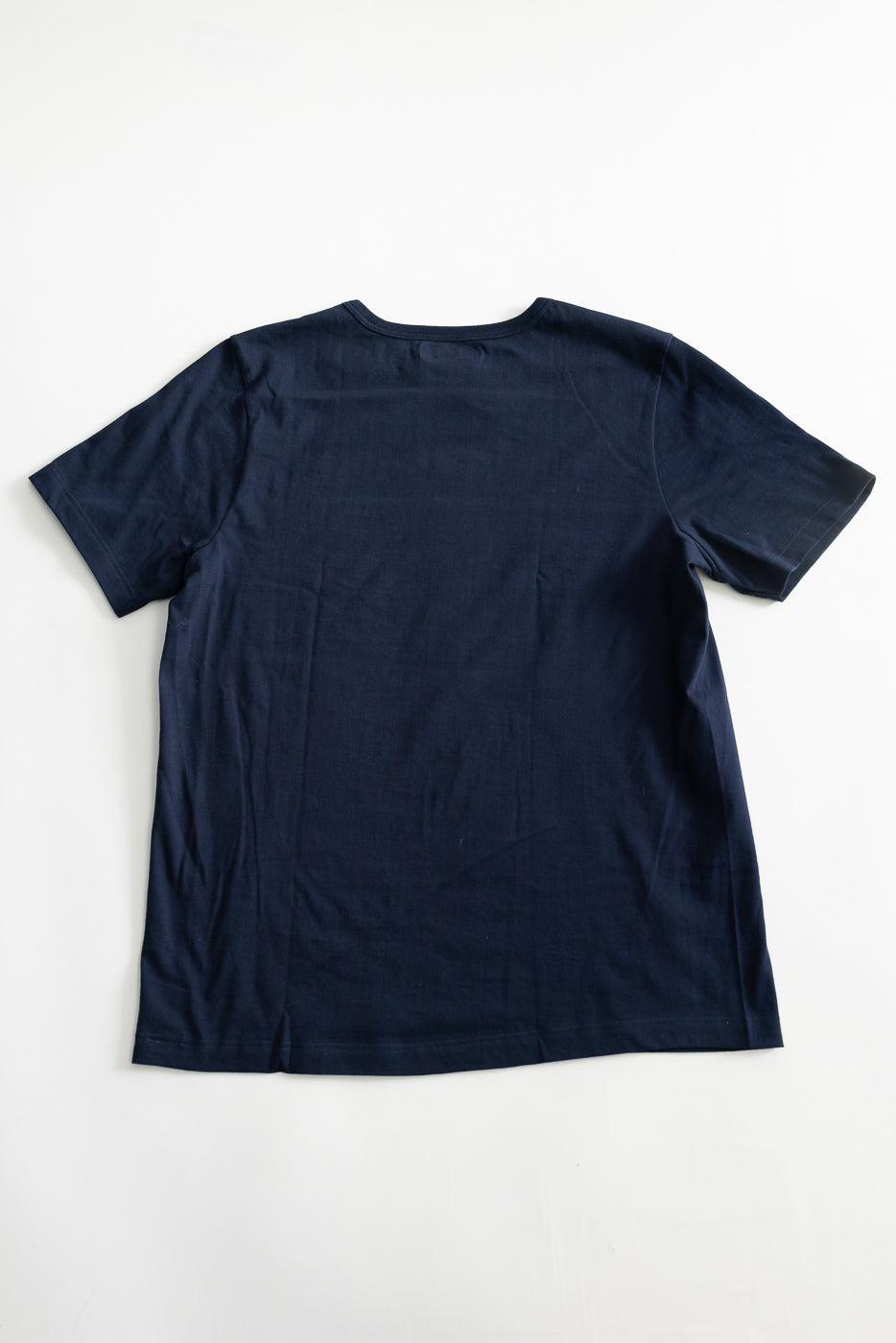 Flat lay of classic fit ink blue t-shirt, back side, showing short sleeves and straight hem.