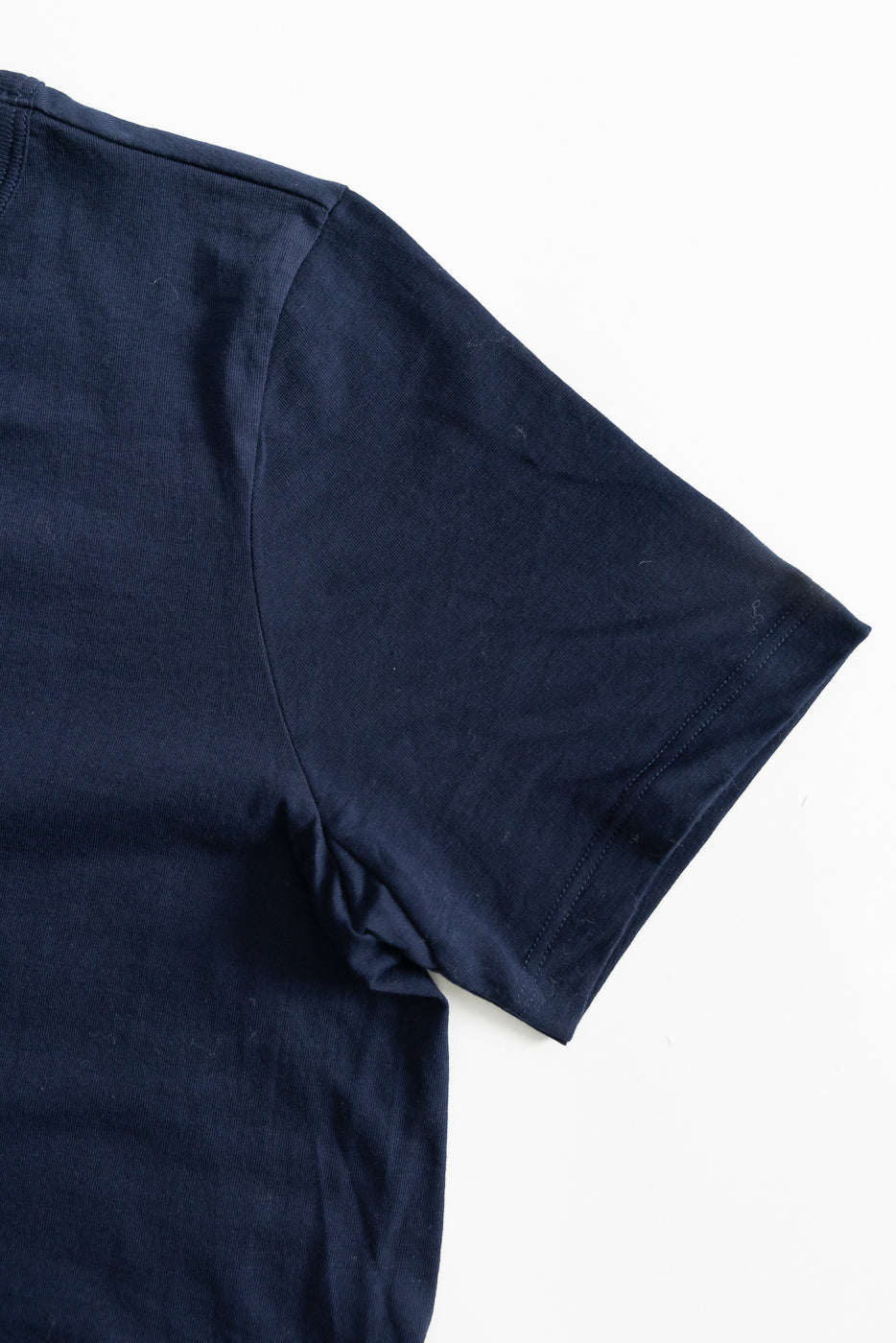 Close-up of short sleeve and shoulder seam, right side, navy blue loopwheeled t-shirt.