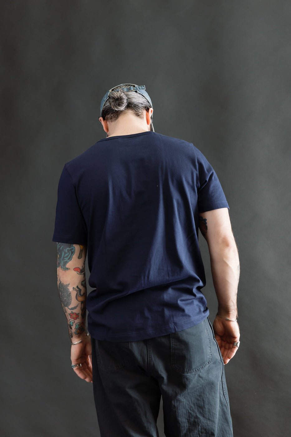 Male model 5'9 165lbs athletic build wearing ink blue t-shirt, back view, full body