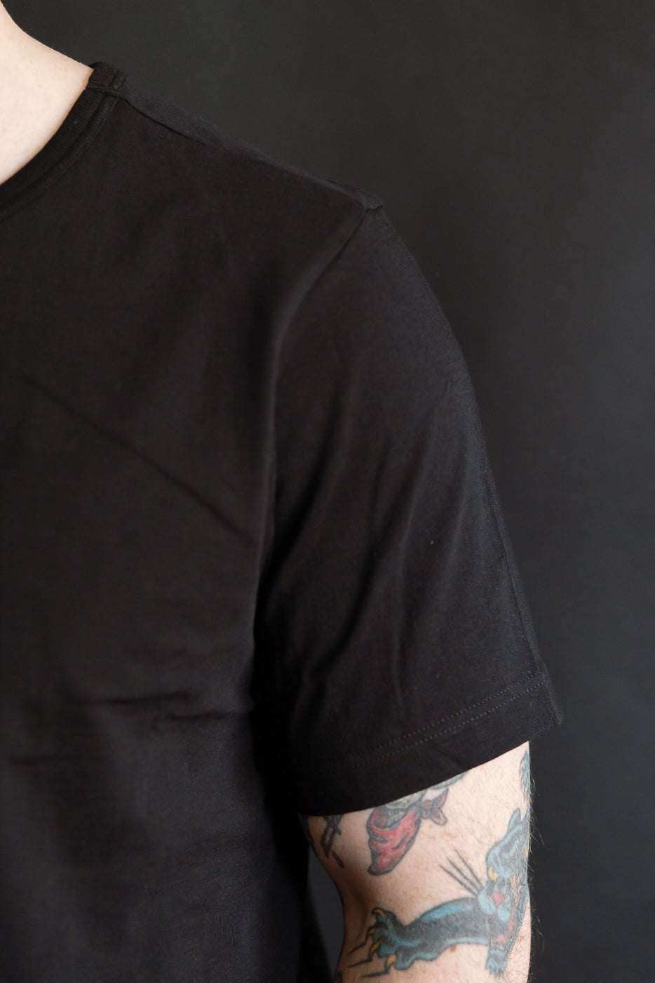 Close-up right side of Merz b. Schwanen 1950s deep black loopwheeled T-shirt sleeve, male model, Dant