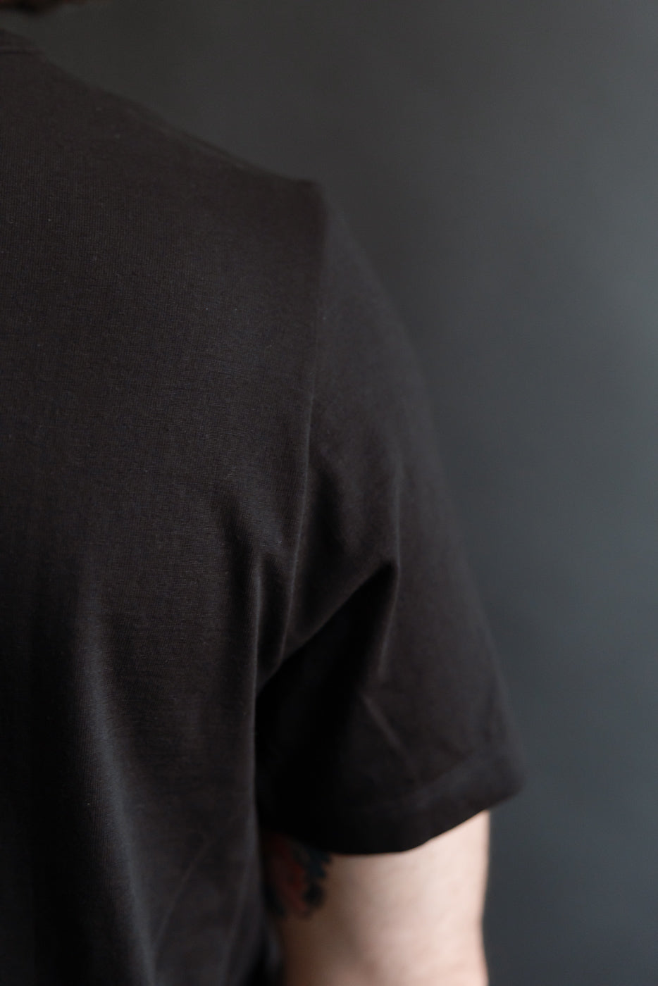 Close-up of men's deep black loopwheeled T-shirt, right shoulder and sleeve shown