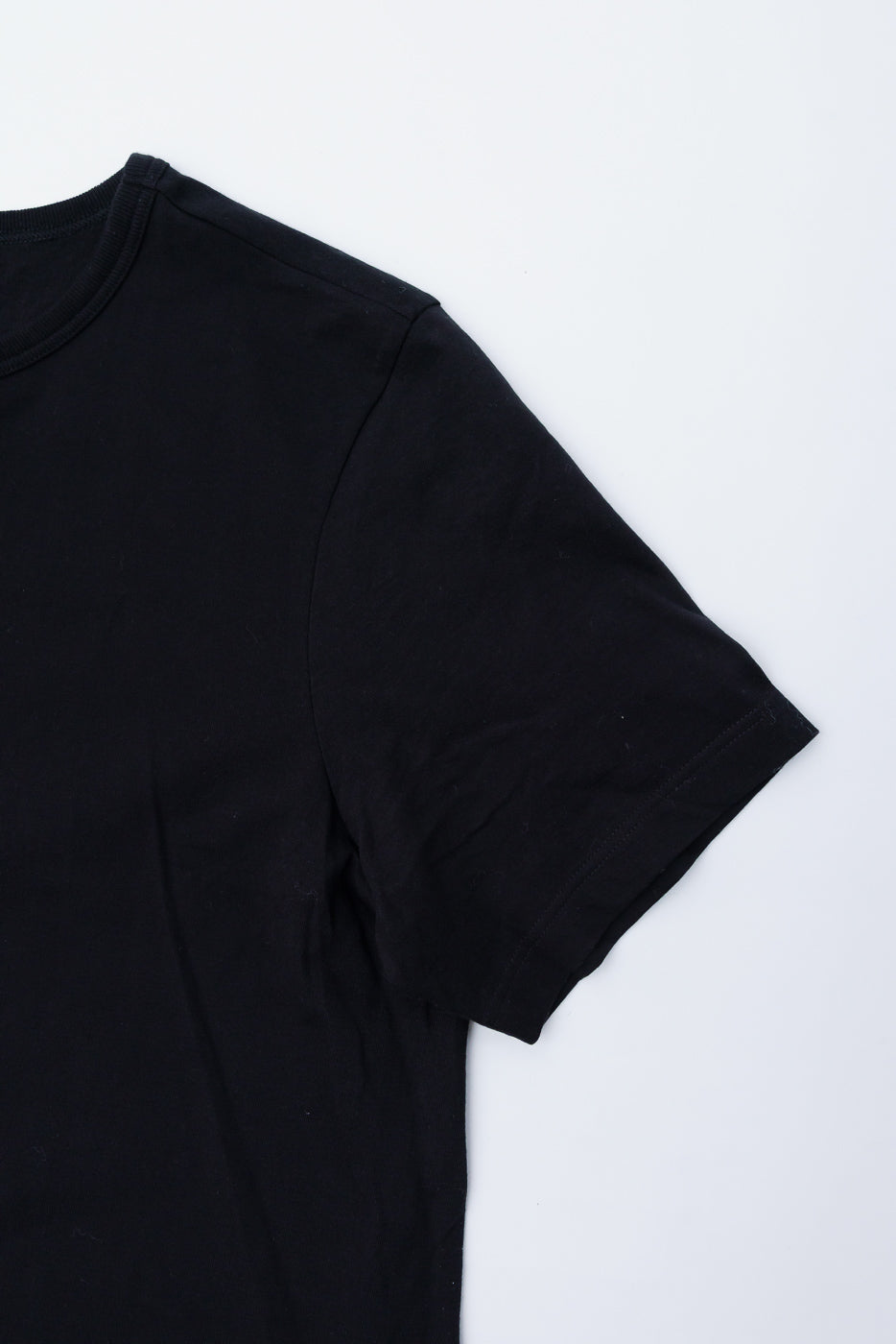 Close-up of front right shoulder and sleeve, deep black loopwheeled classic fit t-shirt.