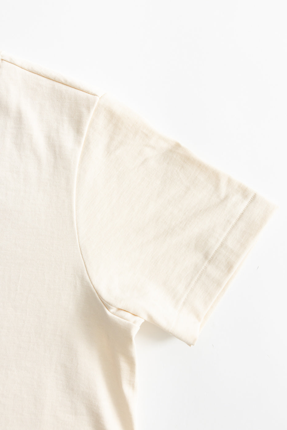 Close-up of short sleeve and shoulder seam, front right side, natural color t-shirt