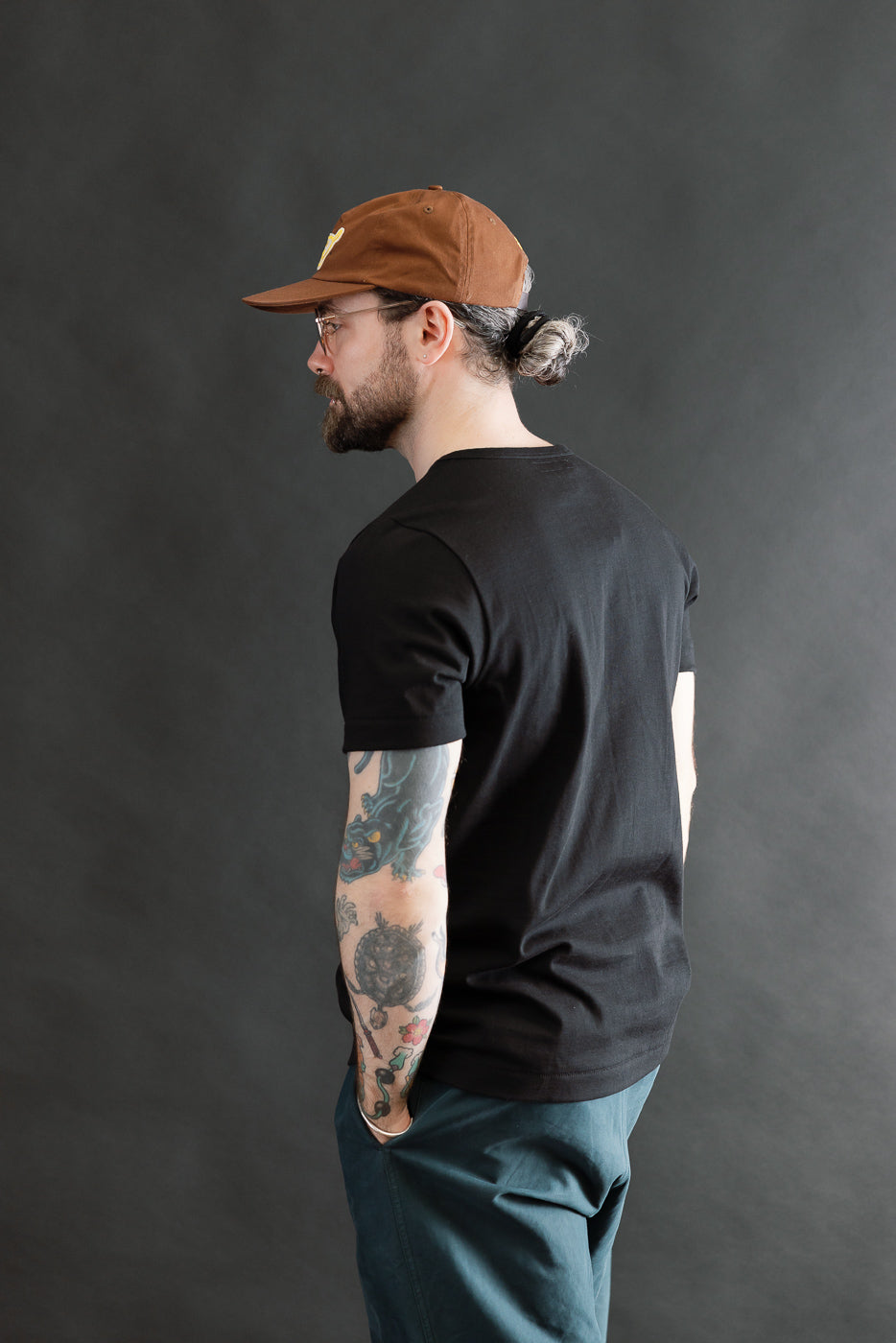 Man in profile wearing the 215.99 - 7.2oz Loopwheeled T-Shirt Classic Fit - Deep Black, showcasing its texture and fit, paired with dark trousers, emphasizing the shirt's classic, comfortable design.