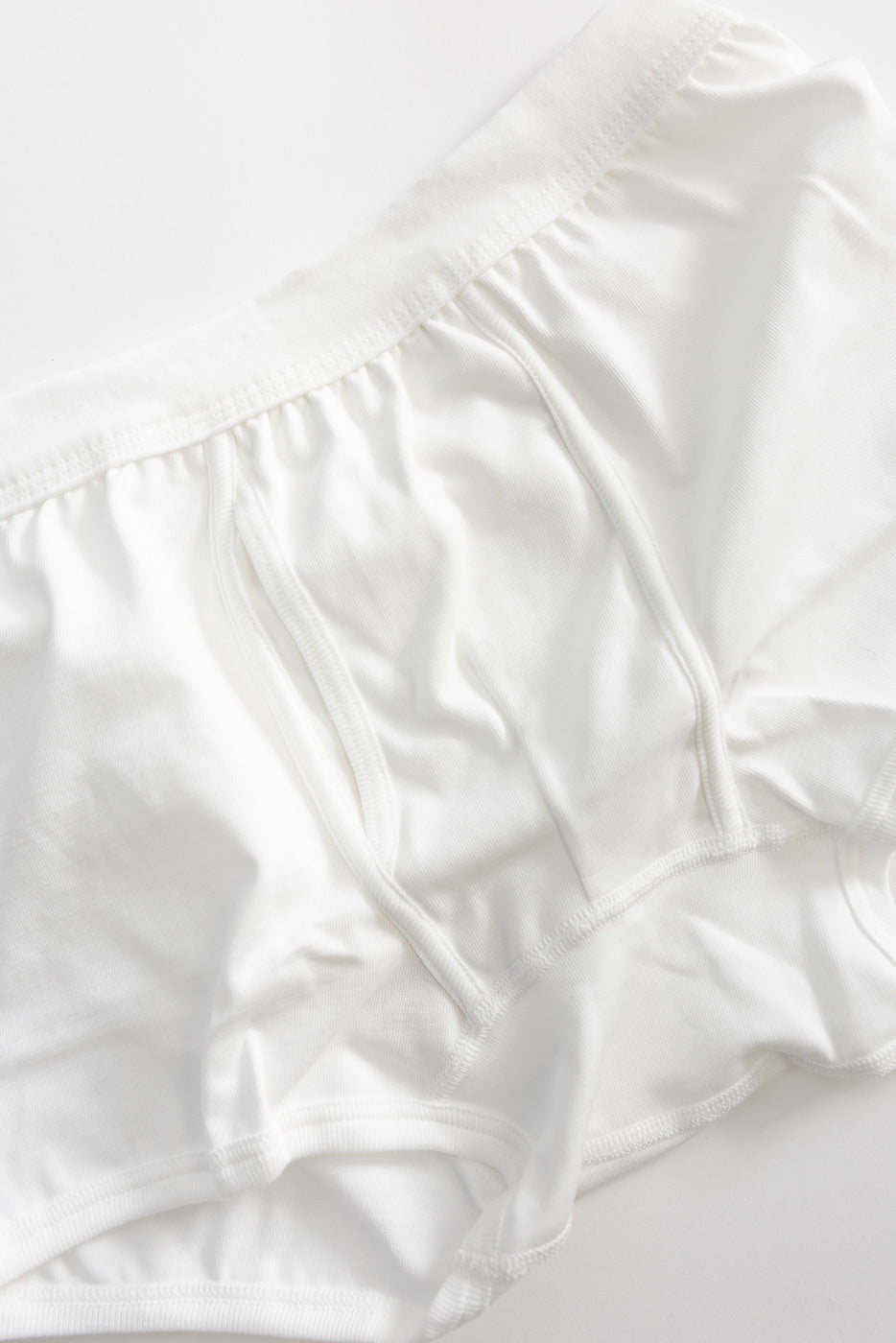 Close-up of front panel and waistband details on white loopwheeled boxer brief, flat lay.