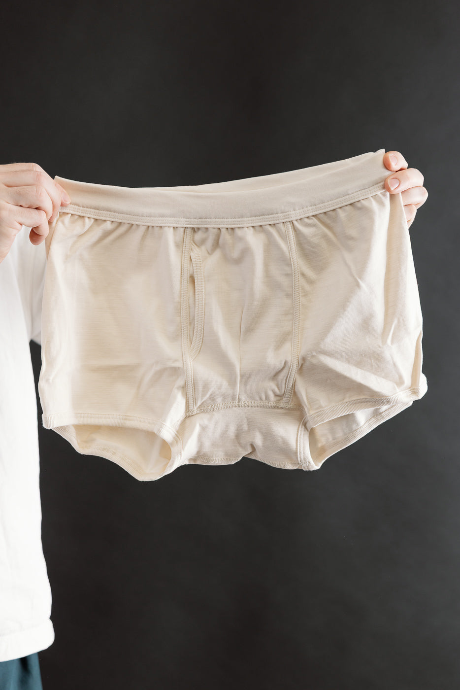 Person holding light-beige 254.02 - Loopwheeled Boxer Brief - Nature, showcasing the waistband and keyhole design, crafted from Merz's 100% organic cotton for Dant’s premium menswear collection.