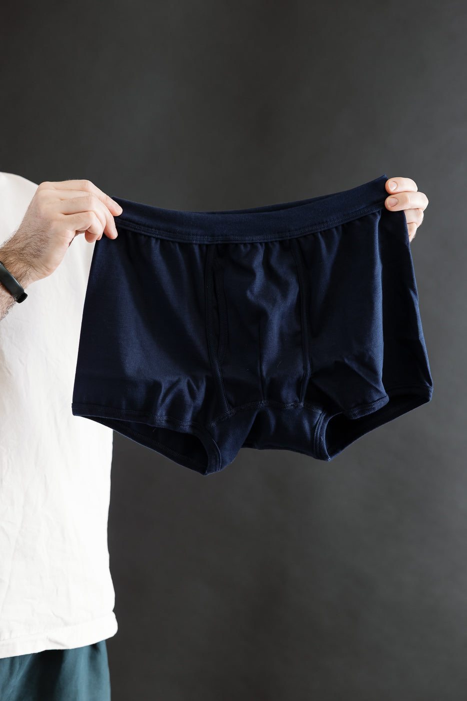 A hand holds the 254.66 - Loopwheeled Boxer Brief in Ink Blue, showcasing its soft, breathable, loopwheeled cotton fabric, elastic waistband, and functional keyhole opening, embodying Dant's refined menswear ethos.