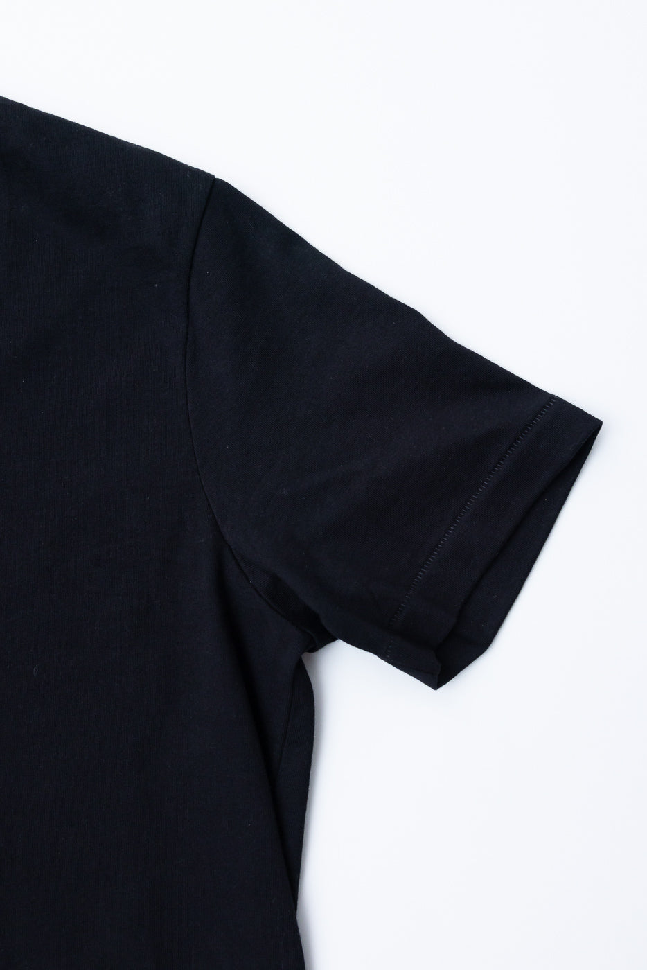 Close-up of the right sleeve and shoulder of a black cotton t-shirt showing fabric texture.