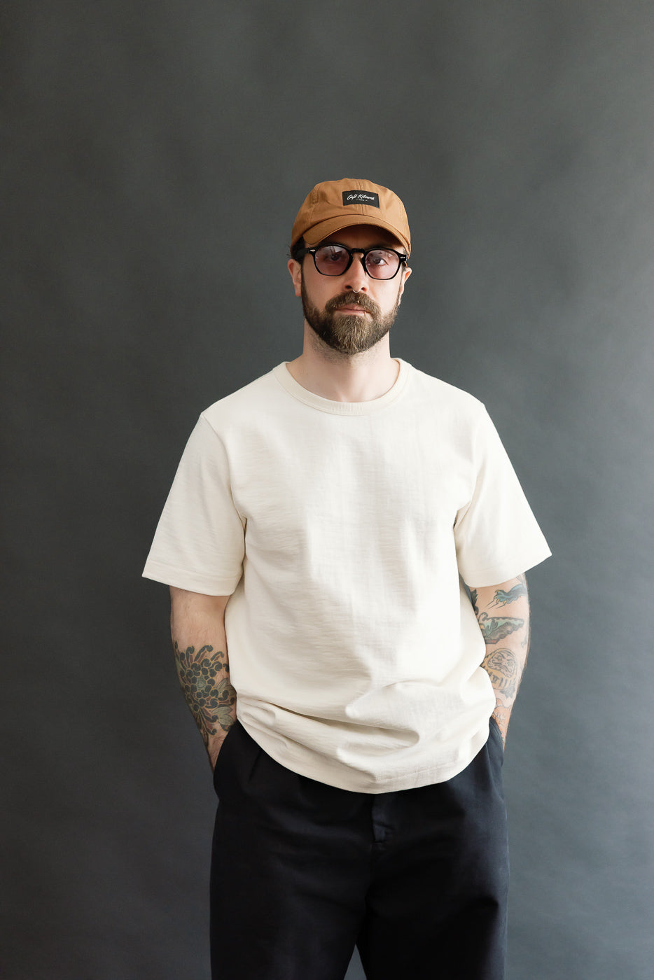 Man in a 2S14.02 - 10.7oz Loopwheeled Heavy T-Shirt Relaxed Fit - Nature, showcasing its relaxed fit and unique fabric texture, paired with dark pants, highlighting a casual and minimalist style.
