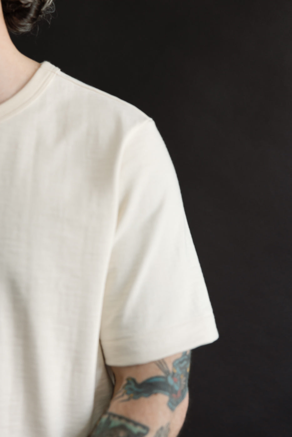 Side view of the 2S14.02 - 10.7oz Loopwheeled Heavy T-Shirt Relaxed Fit - Nature, showcasing its off-white fabric and detailed neckline. The T-shirt's slub texture adds to its casual, comfortable appearance.