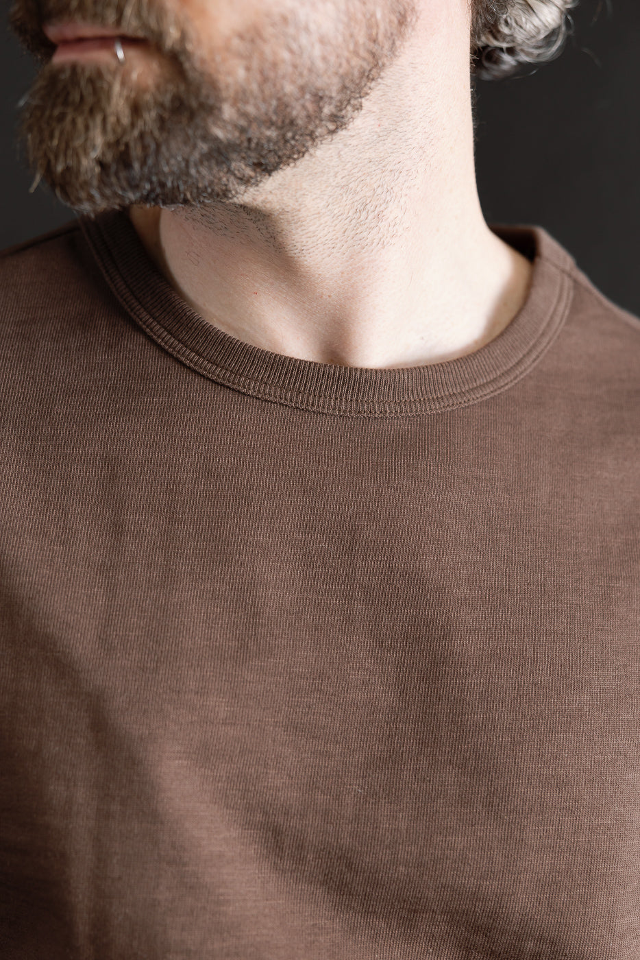 Close-up of crew neck collar and fabric texture, front view, chocolate brown heavy t-shirt on male model, 5'9