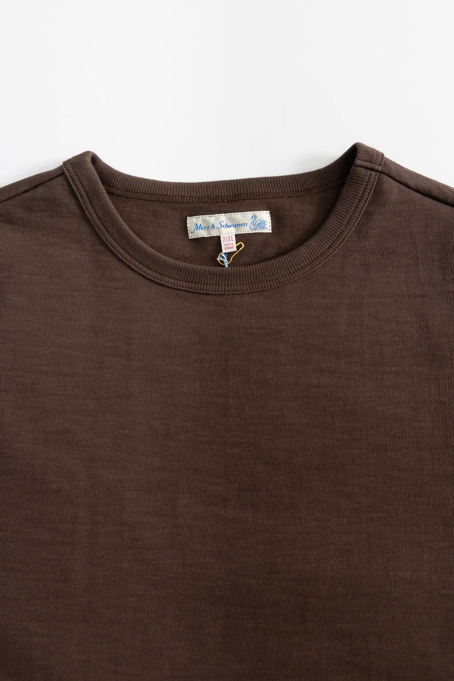 Close-up of chocolate brown heavyweight T-shirt front, showing crew neck, tag, fabric texture