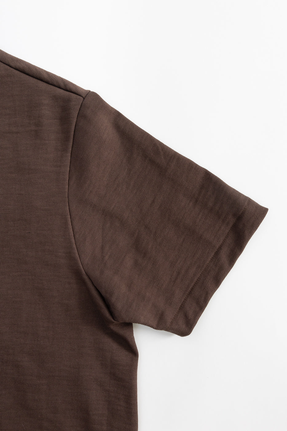 Close-up of chocolate brown heavy T-shirt, flat lay showing right sleeve and side seam.